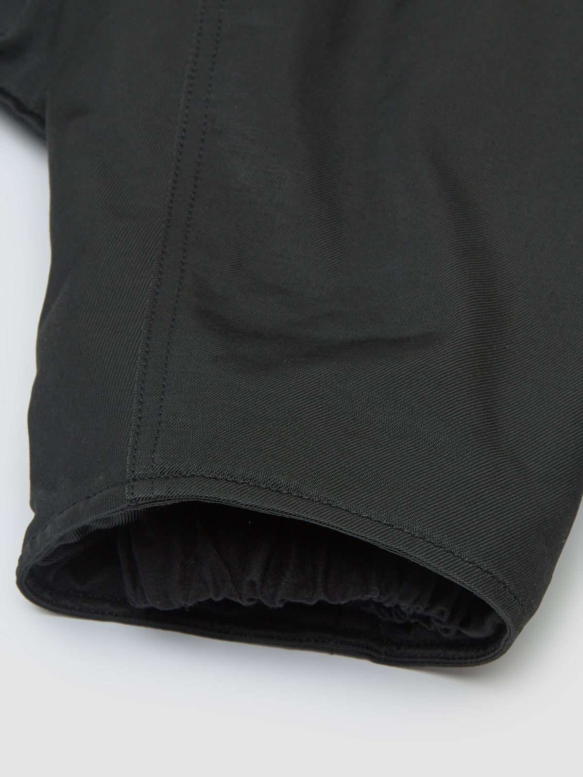 Close-up of a black long sleeve jacket on a light grey background