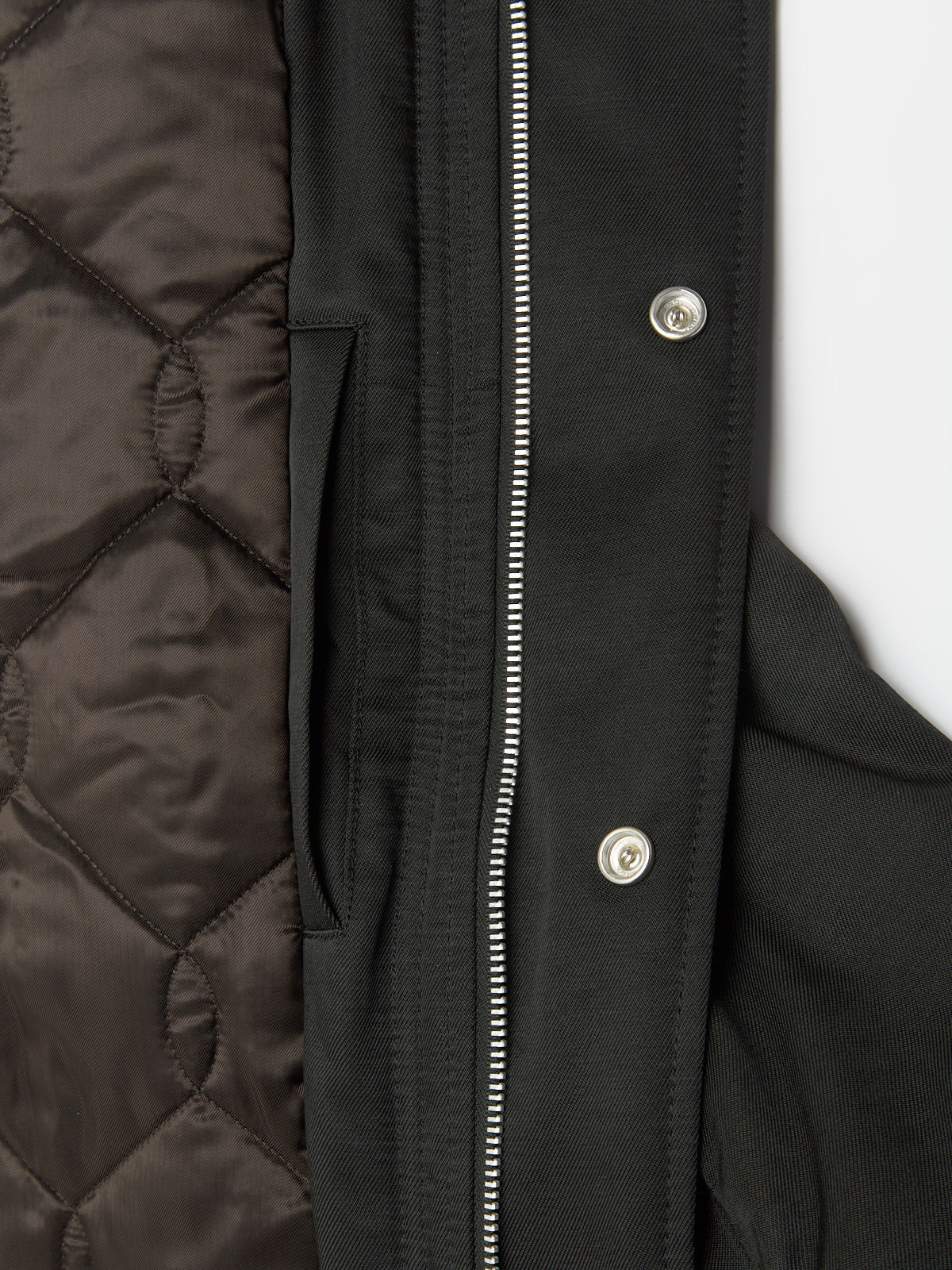 Close-up of a black coat with quilted pattern and zipper details.