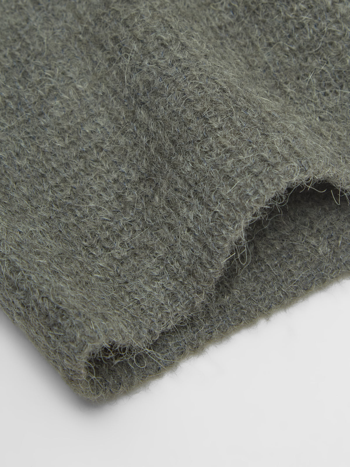 Close-up of green fabric texture on a light gray background