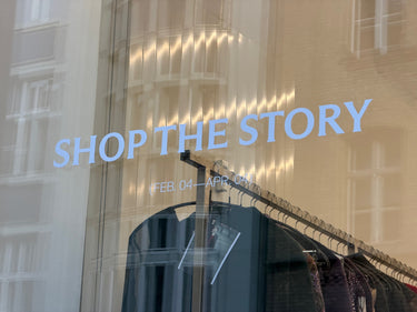 Storefront with 'Shop the Story' sign on a glass window