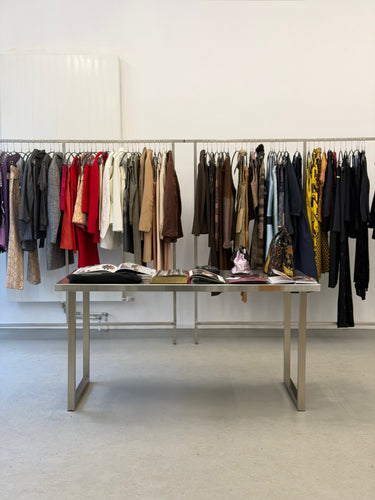 Clothing rack with various garments in a minimalistic room.