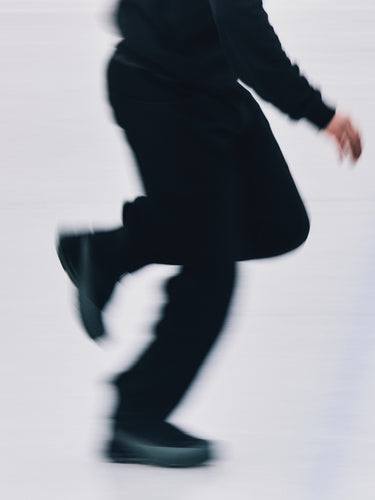Person wearing black shoes and pants on a light gray background.